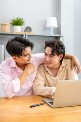 Two Asian men gay couple working together at home using laptop, smiling and bonding