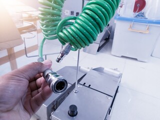 Hand hold the coupler hose air supply pneumatic system compressor on vaccine injector machine.