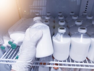 Someone is taking a bottle of animal vaccine inside the vaccine laboratory showcase.