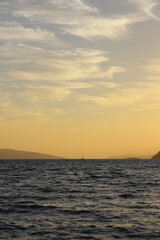 A boat sails through the sea under a golden sky