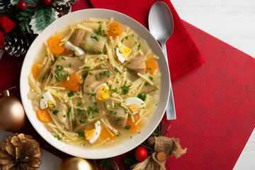 Noodle soup with carrots, artichokes and egg. Top view table with Christmas decoration.