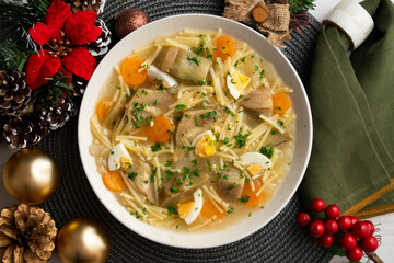 Noodle soup with carrots, artichokes and egg. Top view table with Christmas decoration.