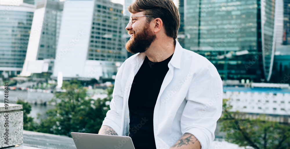 Poster positive male software developer dreaming about statup project sitting in downtown with open modern 