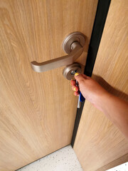 The woman inserted the key into the lock of the front door with her hand. Security and privacy of personal life. Entrance to a room, a space, a house, an apartment. The use of wood and textures