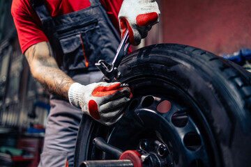 Tire repairman adding some weight to balance the wheel.