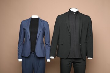 Female and male mannequins with stylish suits on light brown background