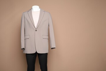 Male mannequin with stylish outfit on light brown background, space for text