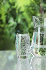 Soda water in glass and jug on light table outdoors