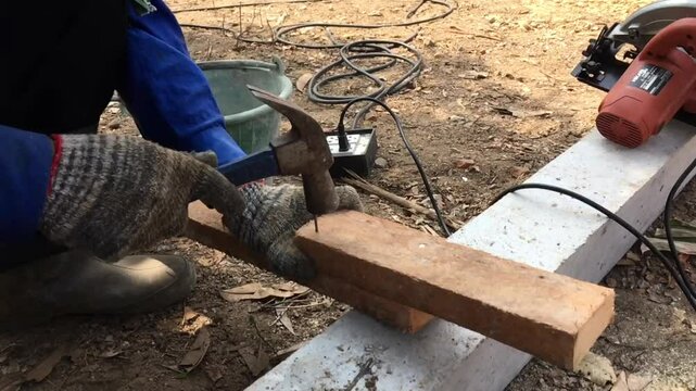 Man Hand With Concrete nails that are driven into the cement floor to tie ropes that will be used to find the width and length of the area