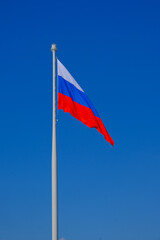 A large flag of the Russian Federation on a blue sky background