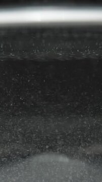 Vertical video. More undissolved powder particles spinning in the water, highlighting the mixing process.