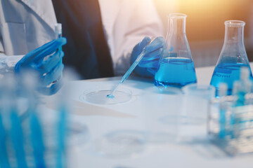 Group of dedicated scientist conduct chemical experiment in medical laboratory, carefully drop precise amount of liquid from pipette into test tube for vaccine drug or antibiotic development. Neoteric