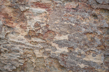Brown grey rough stone wall with peeling of layer stone surface rusted cracks for abstract background and texture, interior or exterior design. Beautiful patterns, space for work, banner, close up.