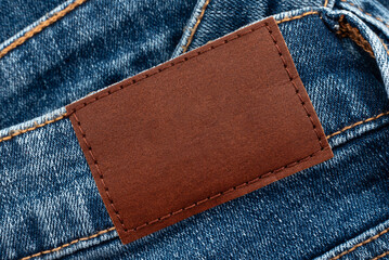 Empty worn leather patch on blue jeans. Empty space for writing. Blank leather jeans label