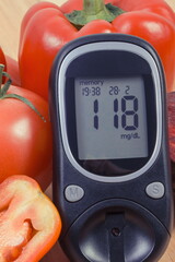 Glucose meter with result of sugar level and fresh natural vegetables. Healthy nutrition during...