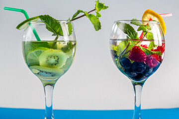 cocktail berry two glasses raspberries blueberries lemon and mint and ivy lime mint in a glass