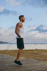 Sideways young strong sporty athletic fit sportsman man wear sports clothes jumping on skipping...