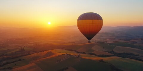 Obraz premium A stunning hot air balloon soaring over serene hills at sunset, creating a picturesque landscape filled with warm colors.