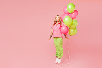 Full body young shocked surprised woman wear shirt celebrating birthday holiday stand hold bunch of colorful air balloons jump high pov fly isolated on plain pastel pink background. Lifestyle concept.