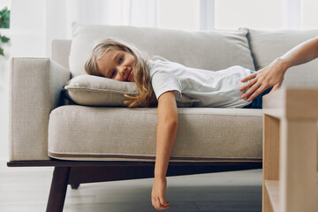 Young girl relaxing on a cozy couch, hands resting on the back, enjoying a quiet moment indoors
