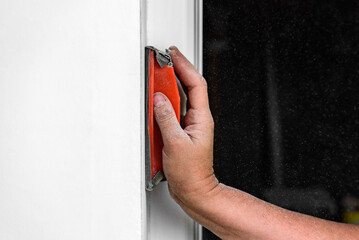 Painter polishing and sanding wall surface after putty for painting in new apartment.