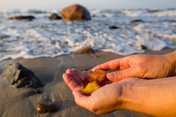 A person is gently holding a beautiful piece of amber