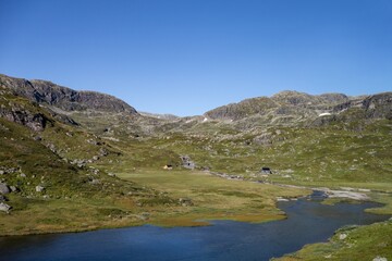 Norwegian rocky landscape with small cottages, mountains and lake