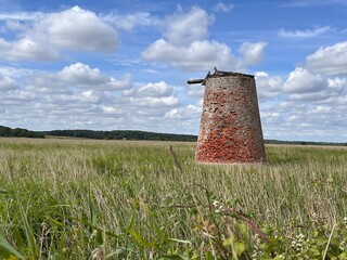 Beautiful landscape of abandoned red brick windmill in a field marsh with reeds with blue sky and white clouds wind mill by the beach on nature reserve in Walberswick Norfolk East Anglia uk in Summer