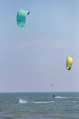 Colorful kites soar above the ocean as enthusiasts enjoy thrilling kiteboarding on a sunny day.