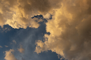 A dramatic sky filled with fluffy clouds illuminated by sunlight, creating a beautiful blend of colors and textures.