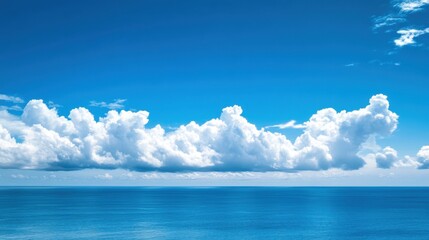 Clear blue sky filled with soft clouds hovering over a vast blue ocean with a peaceful horizon in the distance