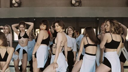 Group of graceful young women dancing indoors. Stylish professional dancers performing sensual dance routine. Young women performing modern dance. Synchronized dance of female. Youth culture. 4K, UHD