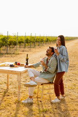 Romantic picnic in a sunlit vineyard featuring a couple enjoying wine and a gourmet platter among the vines during golden hour