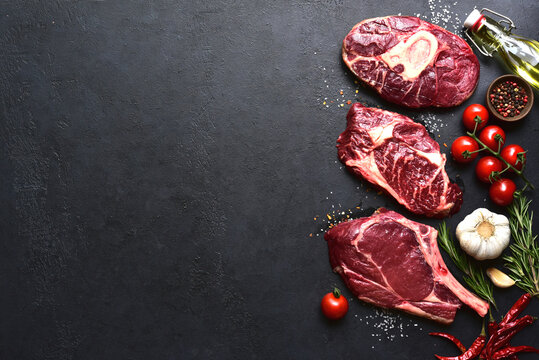 Different types of raw marbled beef steaks : T-bone, ossobuco, spider and rib eye with ingredients for cooking . Top view with copy space.