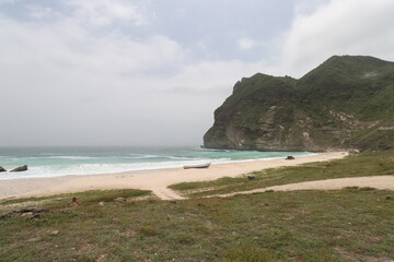 afful beach , the hidden beach in dhofar governorate , sultanate of oman , mountain and cloudy sky	