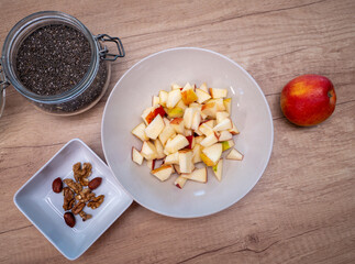 A healthy breakfast made of apple, oatmeal, plain yogurt, walnuts, hazelnuts and chia seeds...