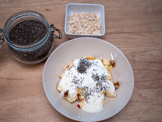 A healthy breakfast made of apple, oatmeal, plain yogurt, walnuts, hazelnuts and chia seeds...