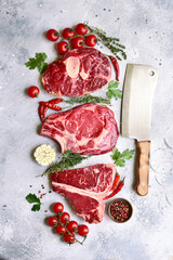 Different types of raw marbled beef steaks : T-bone, ossobuco, spider and rib eye with ingredients for cooking . Top view with copy space.
