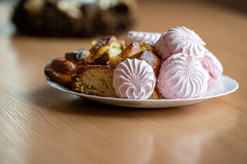 A Colorful Plate of Pastries and Meringues on a Wooden Table in a Cozy Bakery