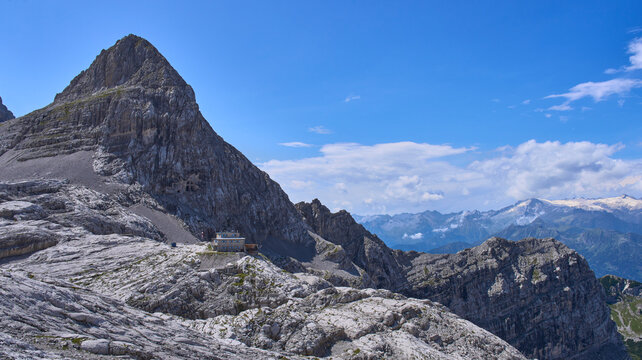 Rifugio XII Apostoli, a starting point for Bocchette path. The refuge stands on a natural balcony of limestone overlooking the underlying Val Nardis. Church behind huge rock cross in the wall of mount