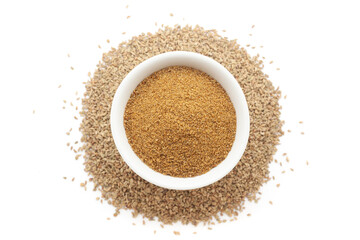 A bowl of Organic Carom seeds (Trachyspermum ammi) or Ajwain powder, placed over a heap of whole Carom Seeds. Isolated on a white background.
