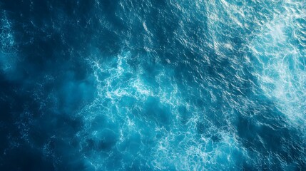Aerial view of swirling ocean waves and currents, creating a dynamic and textured pattern of blue water and white foam.
