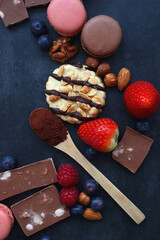 Macarons, chocolate, cookies, berries and various nuts on dark blue background. Top view.