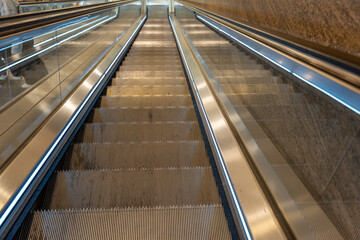 The escalator is very long and has a shiny silver surface. The stairs are very narrow and the steps are very close together