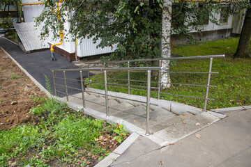 A ramp with a stainless steel railing leads to the building entrance