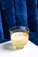 An alcoholic cocktail in a lowball glass served on ice and garnished with orange peel