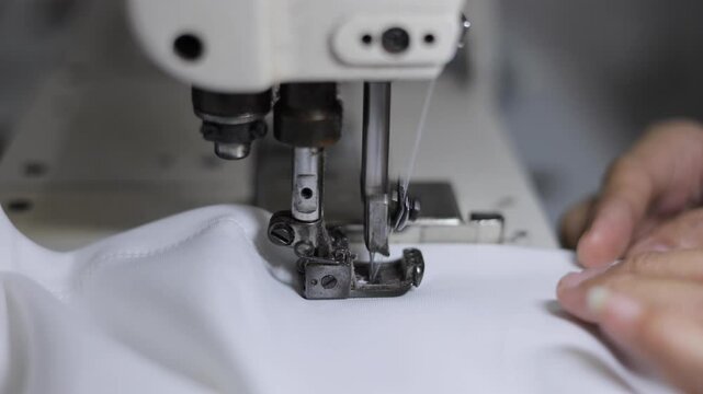 Sewing machines are working, producing clothes in a factory.	