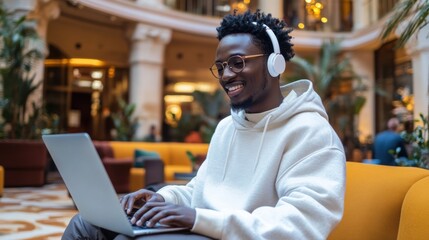 Fototapeta premium Young man working on laptop while listening to music in a cozy café