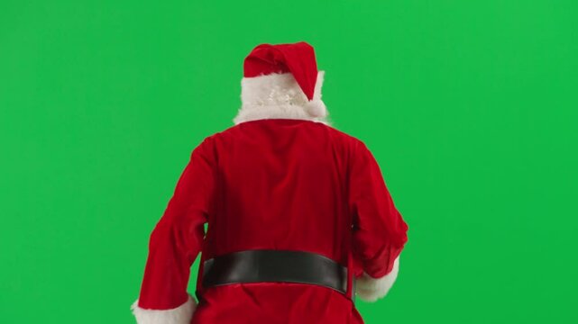 Portrait of man dressed as Santa on chroma key green screen background. Santa Claus in red outfit with beard and mustache running. Back view.