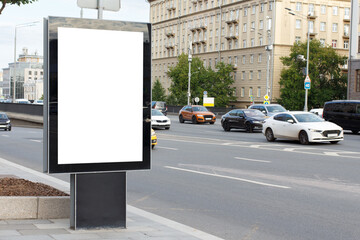 White blank vertical billboard in the city. Light beige building, highway. Mock-up.